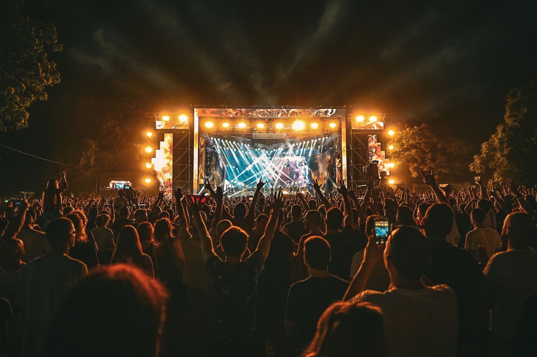 Grande foule profitant d'un spectacle de concert en plein air spectaculaire la nuit avec des effets d'éclairage de scène.