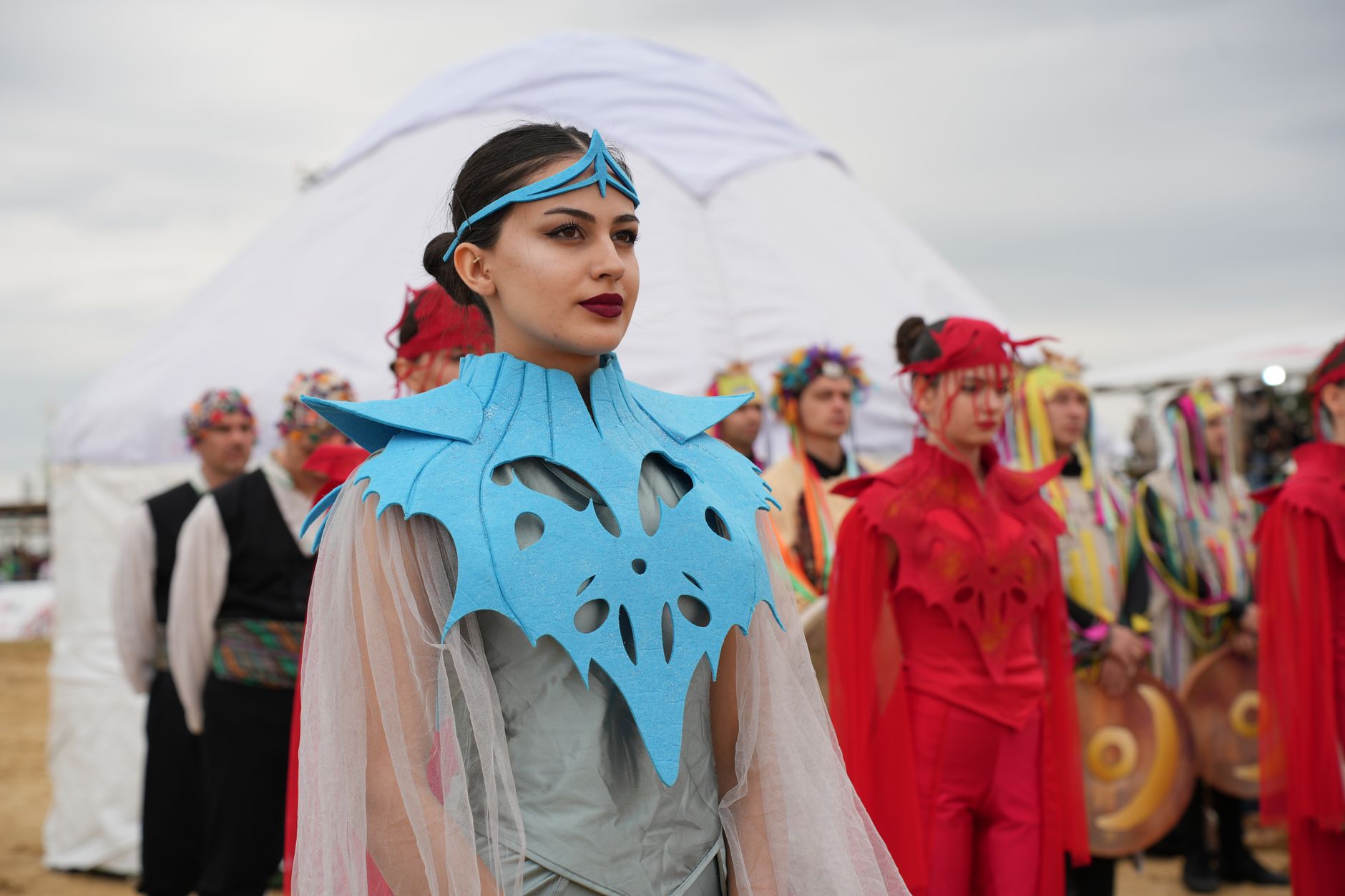 Vibrant cultural festival scene featuring performers in ornate traditional costumes outdoors.