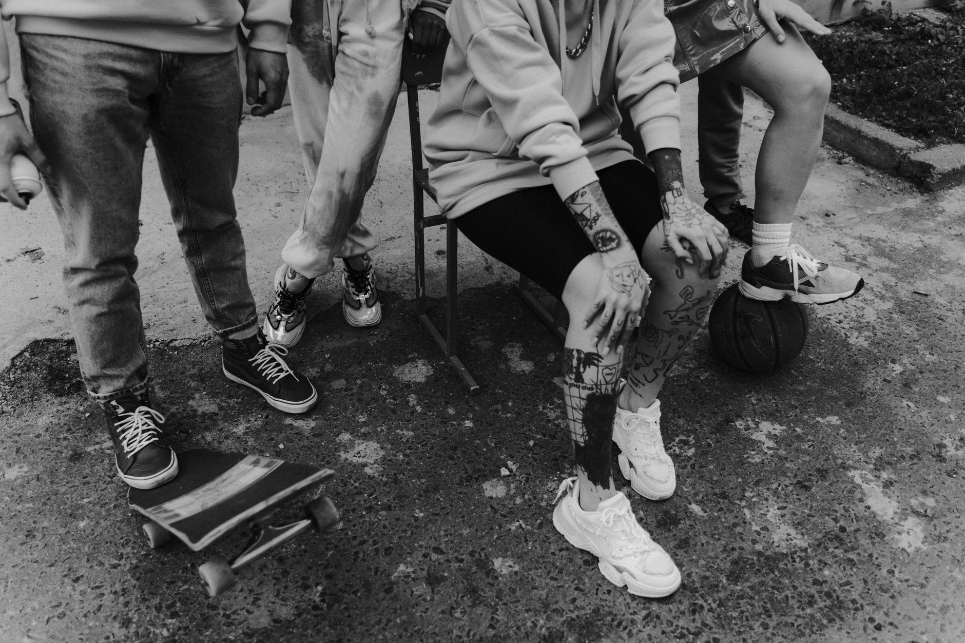 Black and white photo of urban youth fashion with tattoos and streetwear style.