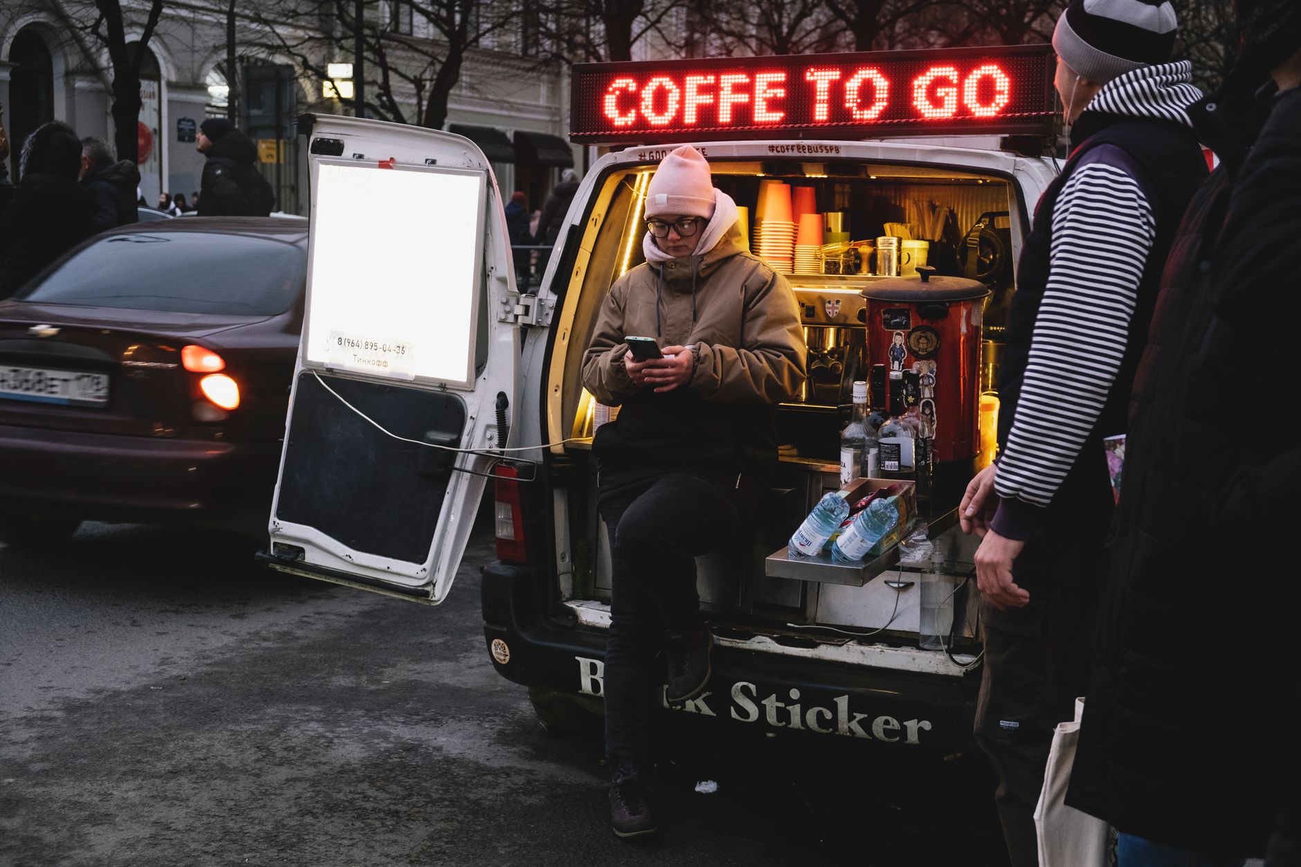 A mobile coffee van serves customers on a bustling street, enhancing urban daily life.