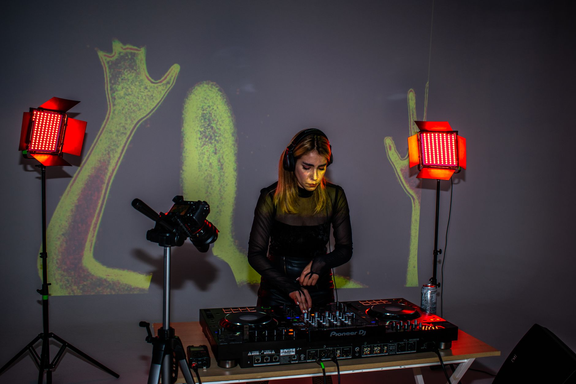 A female DJ mixes electronic music at an indoor event. Captured with vibrant lighting and artistic visuals.