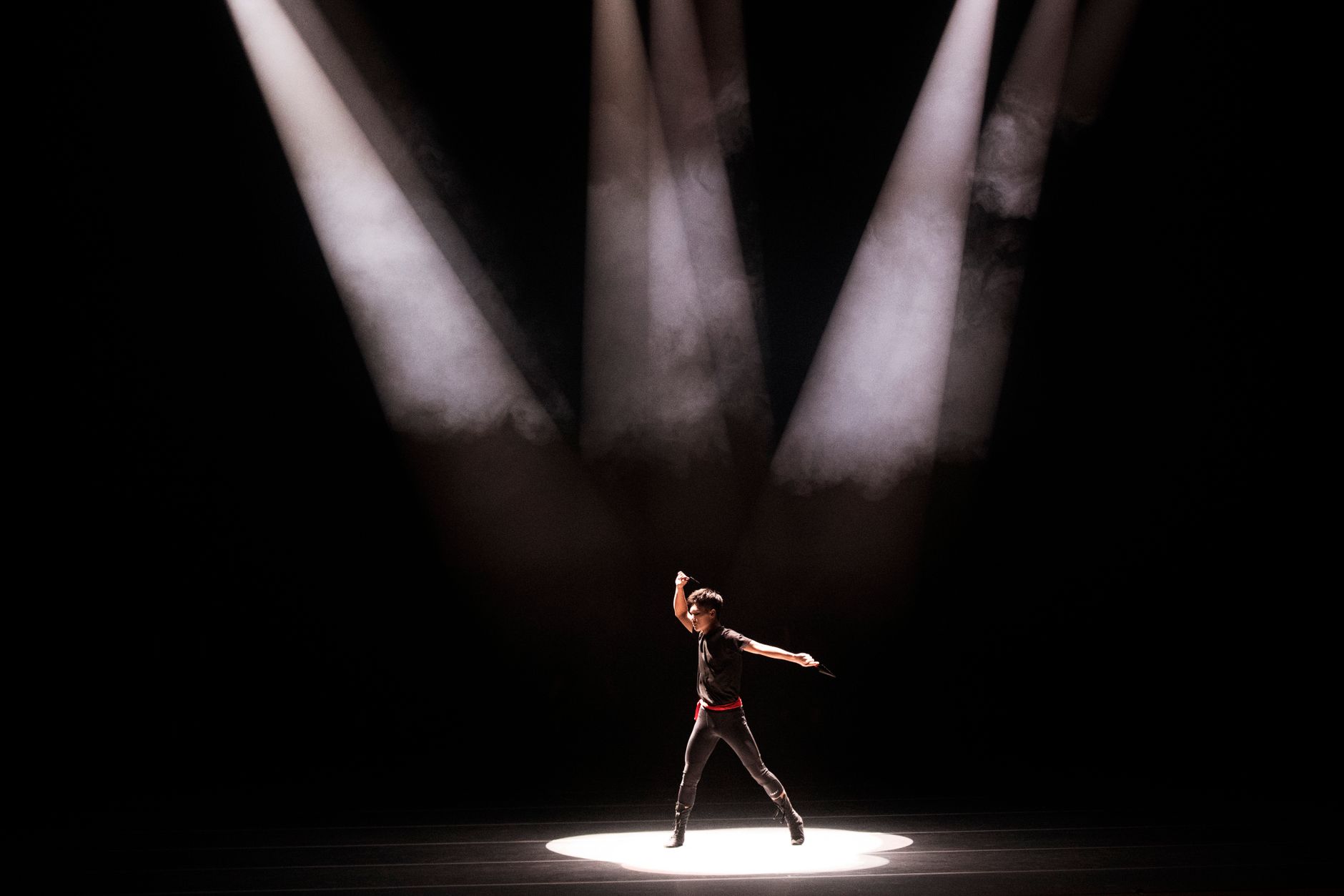 Performance énergique d'un danseur masculin sous un éclairage théâtral dramatique.